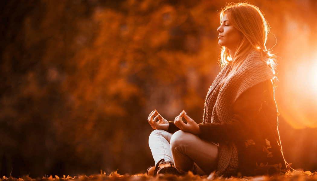 A close-up of a woman meditating at sunset