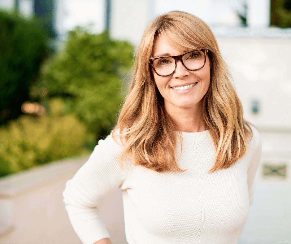 A blonde friendly-looking woman with glasses